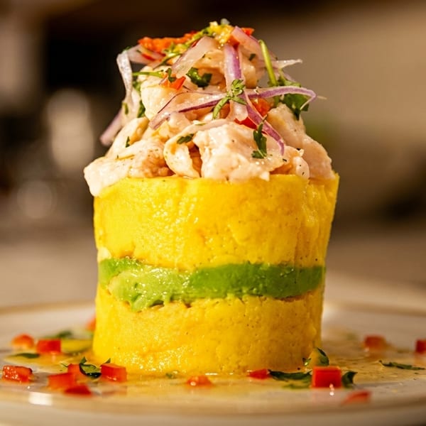 Peruvian causa, a yellow potato terrine layered with green avocado and topped with ceviche.